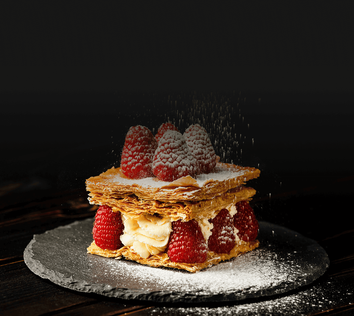 A plated dessert of pastry layers, cream and strawberries