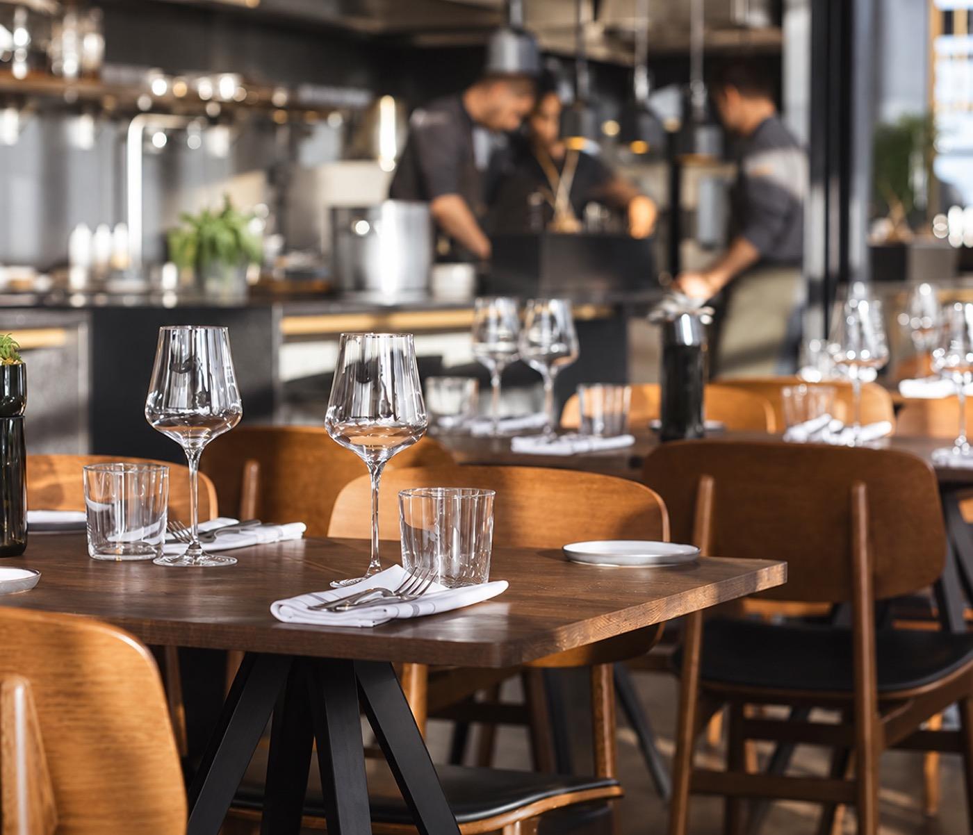 A restaurant dining room set for service, with the kitchen behind